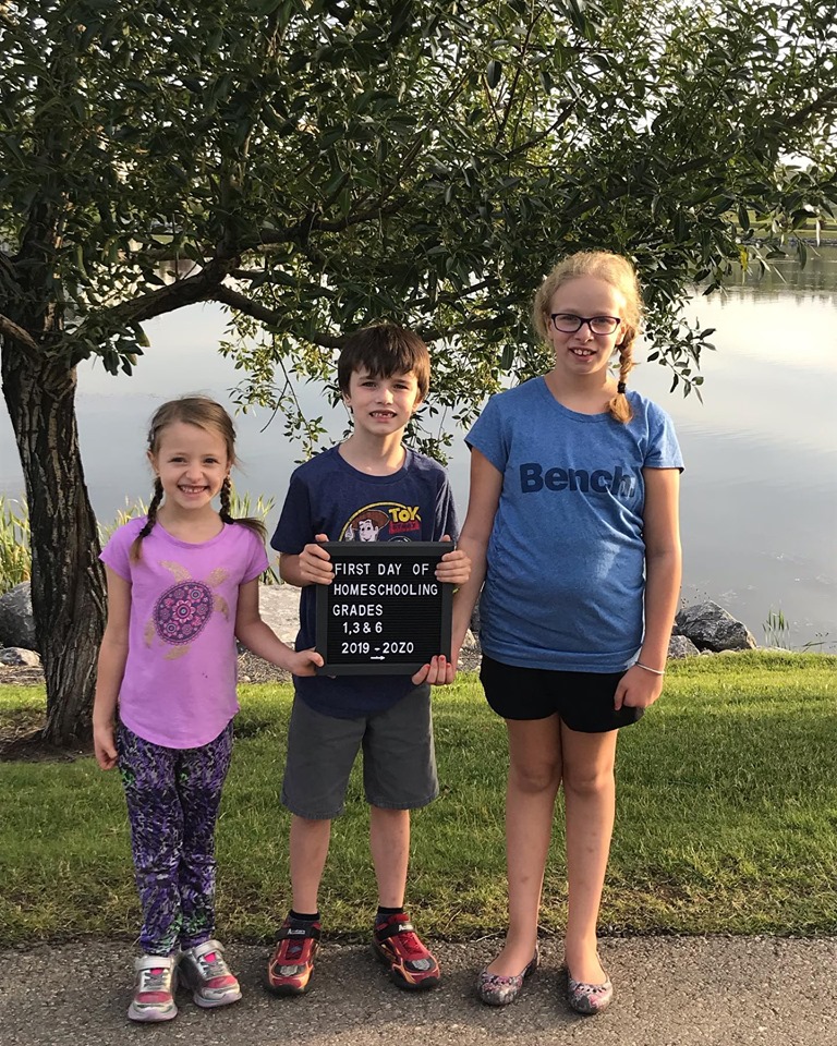 Keera, Zaden, and Emilee holding their first day of homeschooling sign