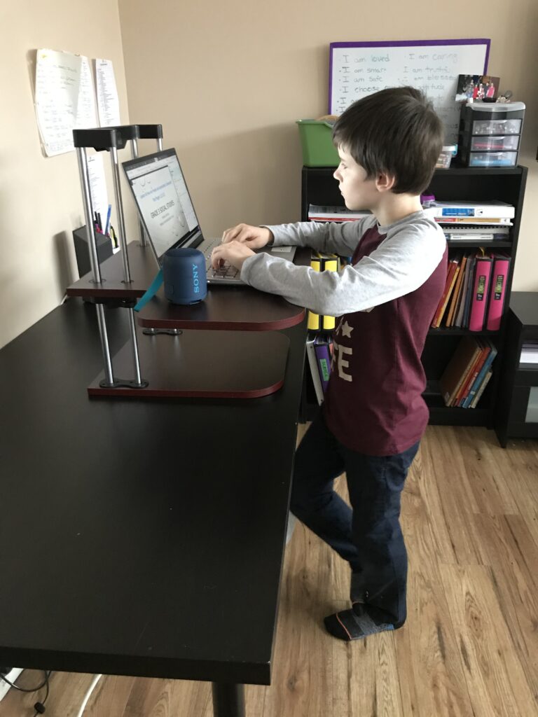 Zaden using The AnthroDesk Standing Desk Converter to do his live sessions for school.